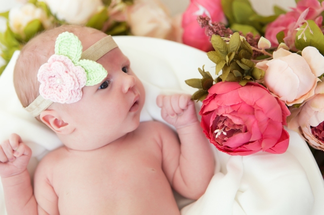 Newborn baby lies in flowers close up